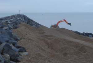 Recovery of beach material by digger from behind the rock spur on the western side of the harbour arm